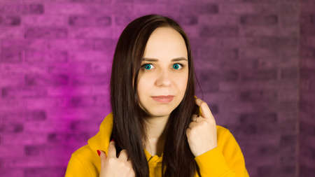 Young female smiling and looking at camera against illuminated wall. Close up of smiling woman with green eyesの写真素材