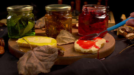 Slice of bread with jam. Man smears fresh jam on bread slice on a black background. Closeup of...