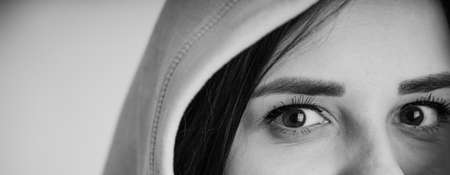 Portrait of young woman looking at camera. Close up of pretty female in hoodの写真素材