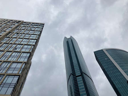Facade of modern skyscraper with glass walls. From below of contemporary tall skyscraper with glass walls against cloudy sky in downtown.の写真素材