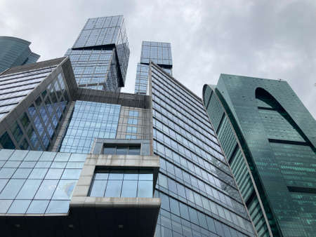 Facade of modern skyscraper with glass walls. From below of contemporary tall skyscraper with glass walls against cloudy sky in downtown.の写真素材