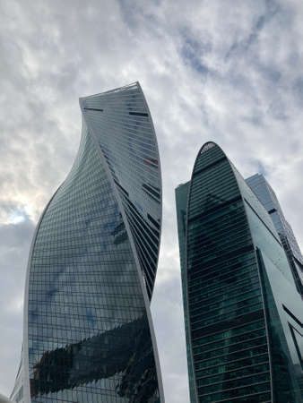 Facade of modern skyscraper with glass walls. From below of contemporary tall skyscraper with glass walls against cloudy sky in downtown.の写真素材