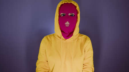 Portrait of young woman in pink balaclava. Close up of hooligan in mask.の写真素材