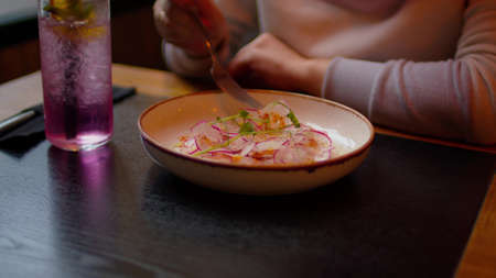 Appetizing snack in plate on table. Unrecognizable woman eats dish in restaurant. Close up.の写真素材
