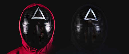 Voronezh, Russia November 2: Unrecognizable people in mask from serial of squid game. Portrait of unknown persons in mask with triangle on black background.のeditorial素材