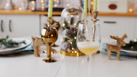 Empty glass on festive table. Unrecognizable person pours light beer into glass while celebration of holidays at home. Close up.の写真素材