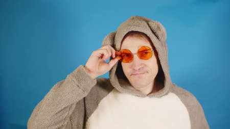 Man in hoodie with ears and sunglasses flaunts on camera. Stylish male changes glasses,の写真素材
