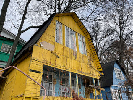 Old yellow wooden house in countryside. Building exterior of shabby unkempt rustic house. Close up.の写真素材