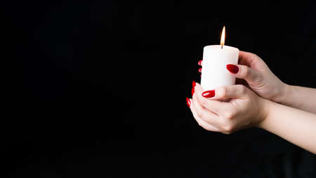 Crop person with burning candle. Crop anonymous person demonstrating white candle black backgroundの写真素材