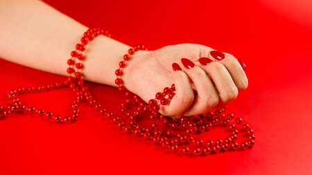 From above of crop anonymous woman with red beads and with red manicure on red background in studioの写真素材