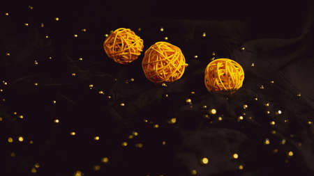 Yellow braided balls on black background. Decorated balls of wood on black veil with beads. Concept...
