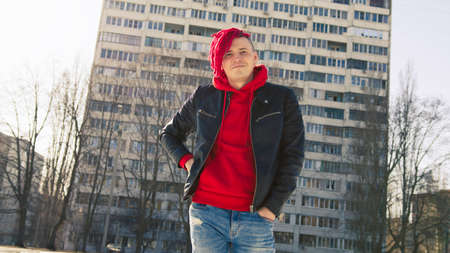 Low angle side of young male in a black leather jacket on street and looking at cameraの写真素材