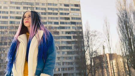 Low angle side view of young female in warm clothes on the street and looking awayの写真素材
