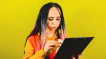 Young woman with working document on yellow background in studio.の写真素材