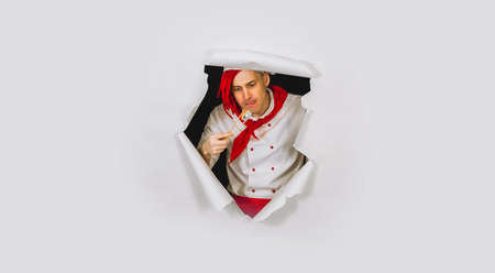 Man dressed as chef wants to eat sushi roll. A male with red dreadlocks looks with appetite at a...