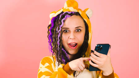 Woman with dreadlocks uses a smartphone and is very and sincerely happy about the online victory. A...
