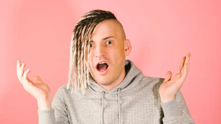 Young handsome shocked man looking at camera with horror on pink background. Emotional blond male with bulging eyes, opening mouth, puzzled facial expression, in state of shock gesturing with handsの写真素材