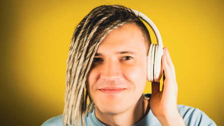 Young handsome man in wireless headphones listening to music through mobile phone. Cheerful guy with...