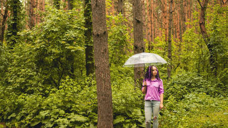 A woman with an umbrella in her hand in the rain. A girl in a purple shirt under an umbrella in the...