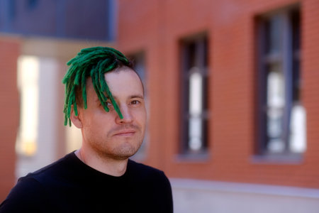 Young handsome man with green dreadlocks in black t-shirt posing on city streetの写真素材