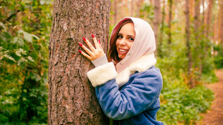 Young happy woman hugging tree with tenderness, love in forestの写真素材