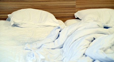 Bed with pillows and crumpled blanket. Crumpled blanket and pillows on empty rumpled bed in hotel...