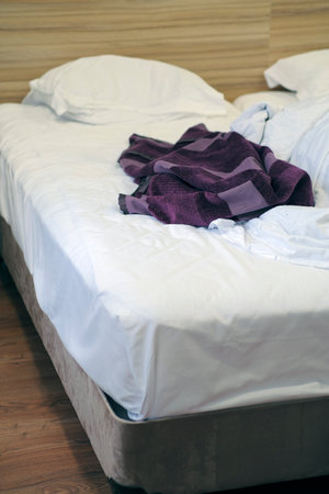 Bed with pillows and crumpled blanket. Crumpled blanket and pillows on empty rumpled bed in hotel...