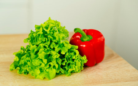 Bulgarian red pepper, green lettuce on table in kitchen. fresh vegetables. close up. food concept. health foodの写真素材