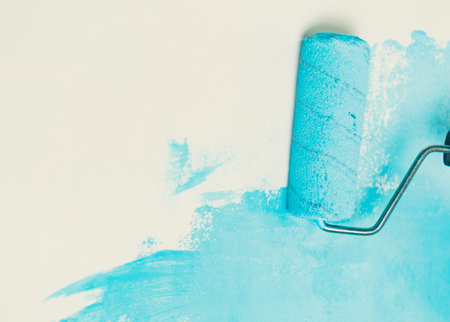 Unrecognizable person applying blue paint on wall. Female hand with roller painting wall. Concept of repair work and improvement of housing conditionsの写真素材