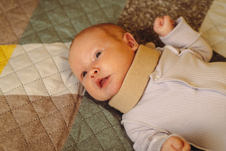 Cute newborn baby in a neck brace. Kid wearing cervical collar, Treatment of spinal injury in a...