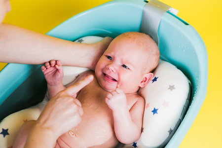A newborn baby takes a bath on a yellow background. A lovely child is undergoing military training...