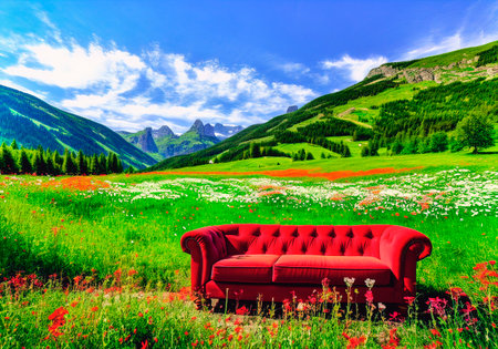 A red sofa on a green meadow with mountains in the backgroundの素材