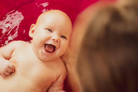Mother bathes her baby in pink bathtub. top view.の写真素材