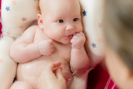 Mother bathes her baby in pink bathtub. top view.の写真素材