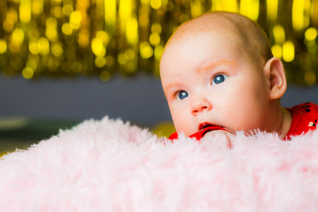 Newborn baby girl with blue eyes on a pink fur blanket.