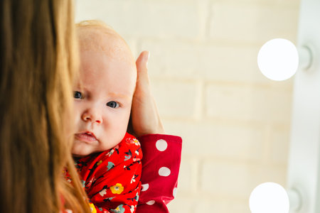Newborn baby girl on mother's hands in red polka dot dress