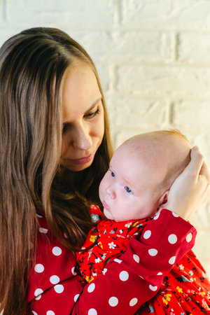 Portrait of mother and baby in red dress on brick wall background