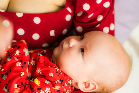 Mother and baby in red pajamas lying on the bed.のeditorial素材