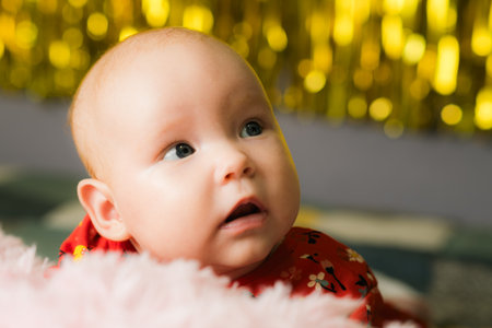 Portrait of a cute baby in a red dress on the background of a Christmas tree