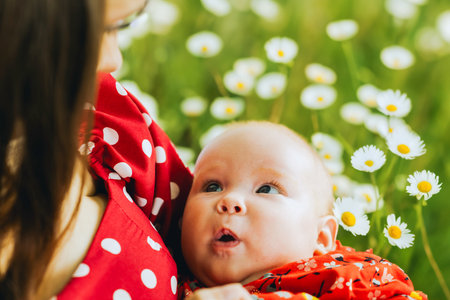 Young mother with her baby in a field of daisies.