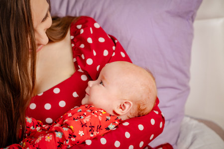 Portrait of a mother holding her newborn baby on the bed.