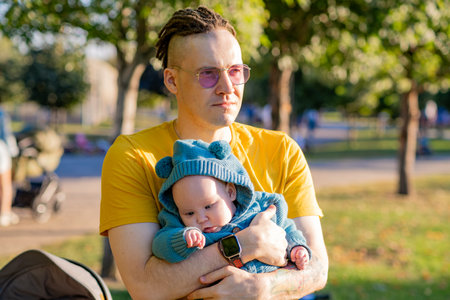 Young father with his newborn son in a park on a sunny day