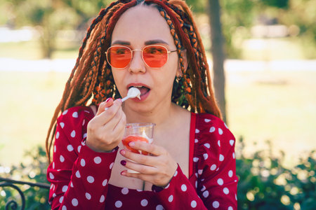 Portrait of a beautiful young woman eating ice cream in the parkの写真素材