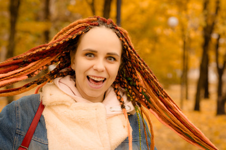 Portrait of a young woman with dreadlocks in the autumn park.