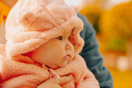 Portrait of a cute little girl in a pink coat with a hood.の写真素材