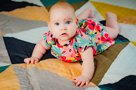 Portrait of a cute baby girl with blue eyes in colorful dress.