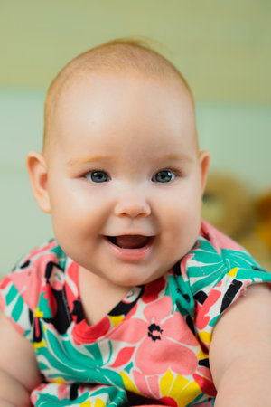 Portrait of a cute little baby girl in a colorful shirtの写真素材