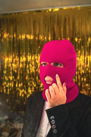 A young woman in a pink balaclava looks in the mirror.の写真素材