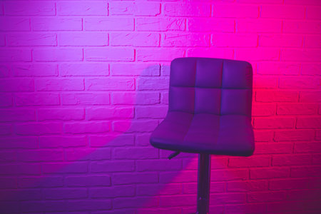 Purple bar stool on a brick wall background in neon light.の写真素材