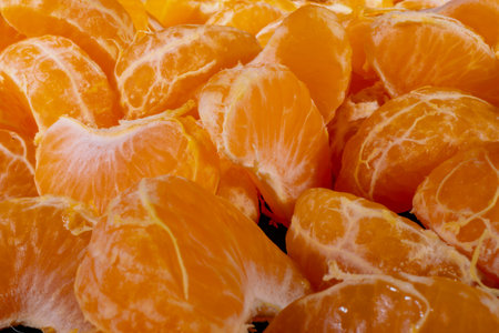 Peeled tangerines on a black background. Slices of tangerine or mandarin fruit close up.の写真素材